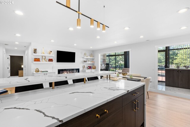 kitchen featuring pendant lighting, a wealth of natural light, dark brown cabinets, and built in shelves