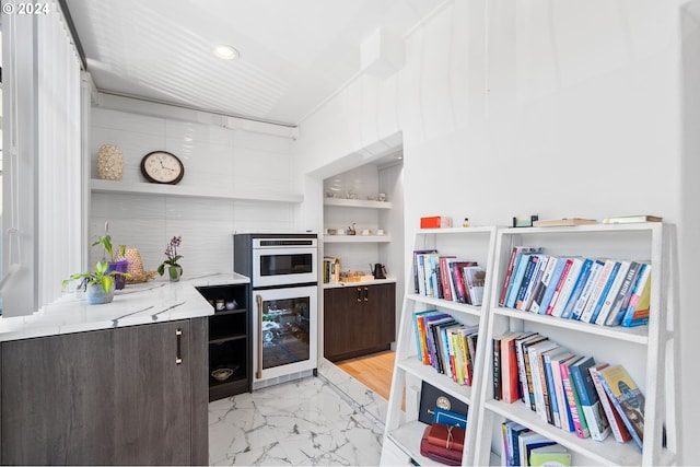 kitchen with dark brown cabinetry, beverage cooler, and white oven