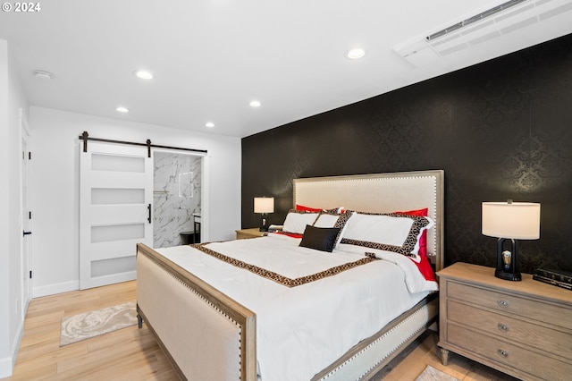 bedroom with a barn door and light hardwood / wood-style flooring