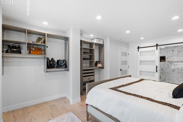 bedroom with a barn door and light hardwood / wood-style flooring