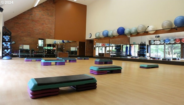 gym with hardwood / wood-style floors and high vaulted ceiling