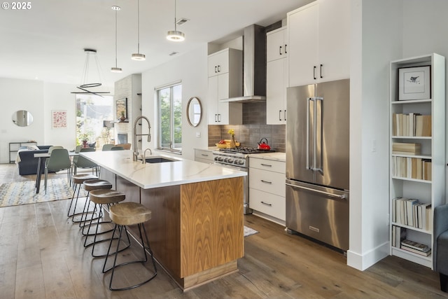 5674 NE 15th Ave, Portland, OR 97211 - kitchen featuring premium appliances, wall chimney range hood, a center island with sink, dark wood finished floors, and tasteful backsplash