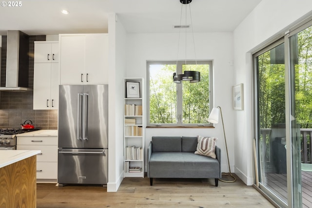 5674 NE 15th Ave, Portland, OR 97211 - kitchen featuring appliances with stainless steel finishes, wall chimney exhaust hood, light wood-style floors, backsplash, and recessed lighting