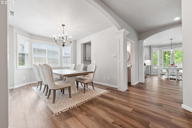 dining room featuring arched walkways, baseboards, and an inviting chandelier