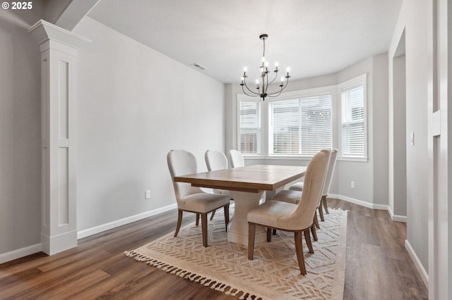 dining room featuring decorative columns, visible vents, an inviting chandelier, and wood finished floors