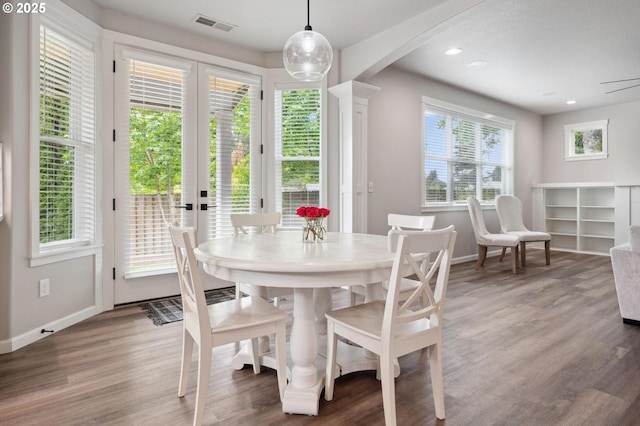 dining room with visible vents, arched walkways, baseboards, and light wood finished floors