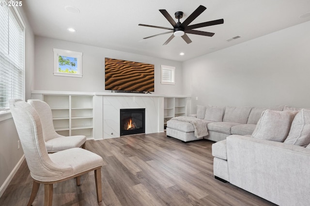 living room with ceiling fan, recessed lighting, wood finished floors, a high end fireplace, and visible vents