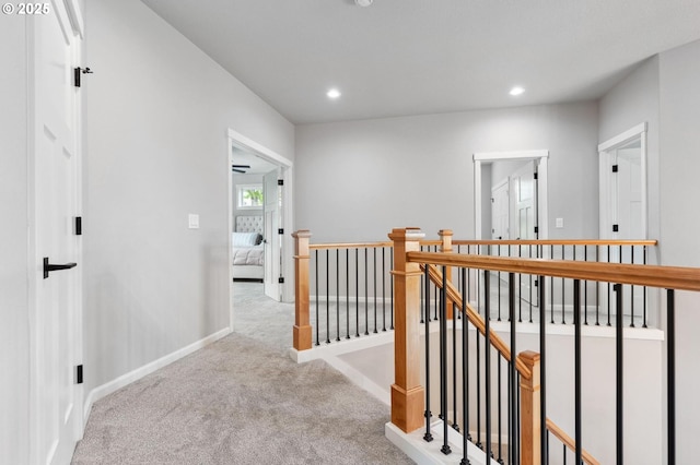 hall with carpet floors, baseboards, recessed lighting, and an upstairs landing