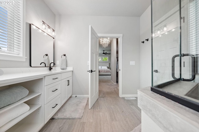bathroom with a stall shower, vanity, baseboards, a notable chandelier, and ensuite bathroom