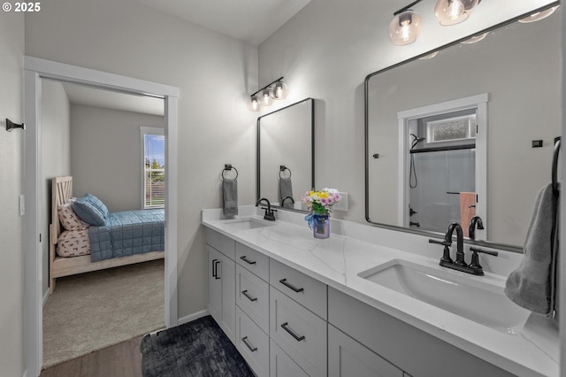 full bathroom with double vanity, a sink, a shower with shower door, and wood finished floors