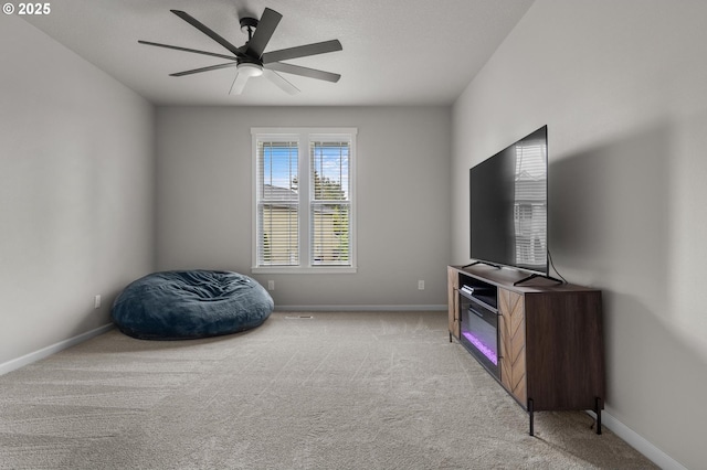 living area featuring baseboards, ceiling fan, and light carpet