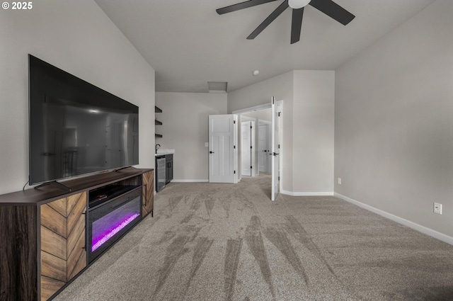 unfurnished living room with ceiling fan, light colored carpet, and baseboards