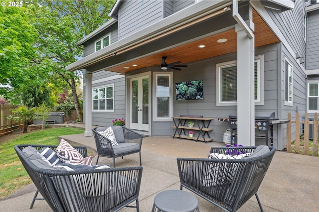 view of patio / terrace with a ceiling fan, french doors, a hot tub, fence, and an outdoor hangout area