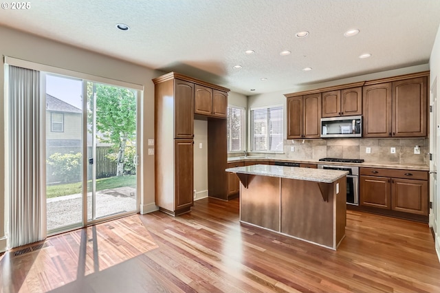 15610 SE Kingbird Dr, Happy Valley, OR 97015 - kitchen featuring stainless steel appliances, a sink, a textured ceiling, light wood-type flooring, and tasteful backsplash