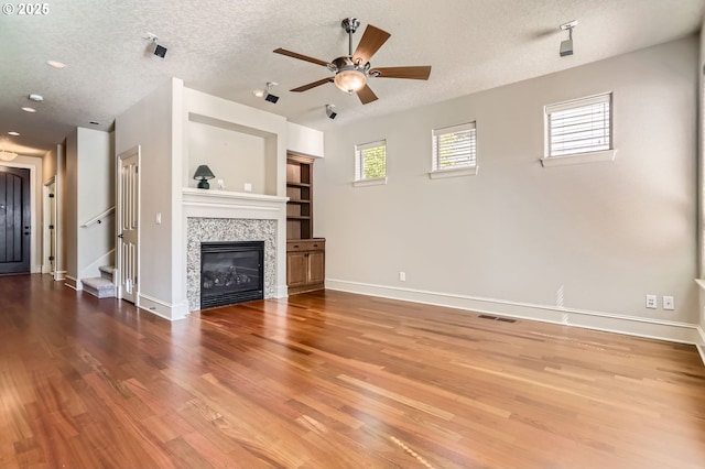 15610 SE Kingbird Dr, Happy Valley, OR 97015 - unfurnished living room featuring wood finished floors, ceiling fan, baseboards, stairs, and a textured ceiling