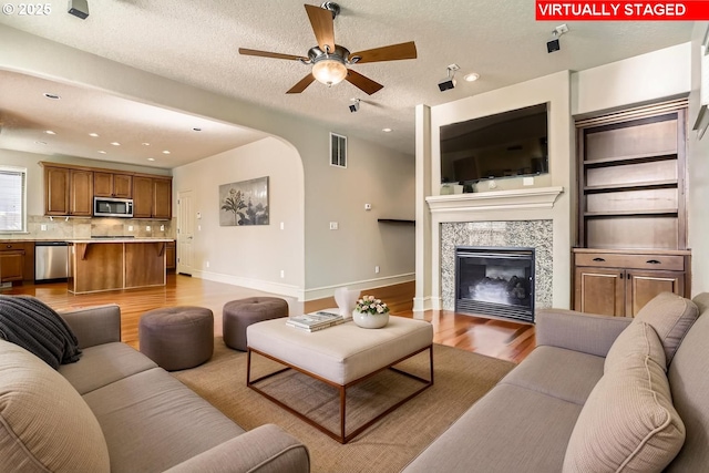 15610 SE Kingbird Dr, Happy Valley, OR 97015 - unfurnished living room with a ceiling fan, arched walkways, a tile fireplace, wood finished floors, and a textured ceiling