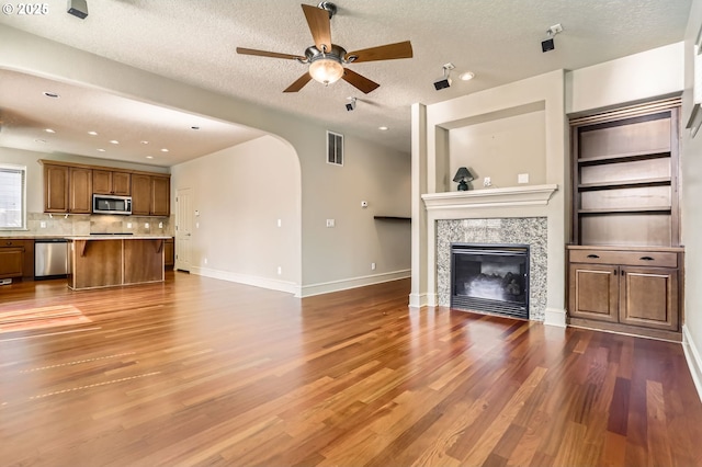 15610 SE Kingbird Dr, Happy Valley, OR 97015 - unfurnished living room with arched walkways, dark wood-style flooring, ceiling fan, baseboards, and a textured ceiling