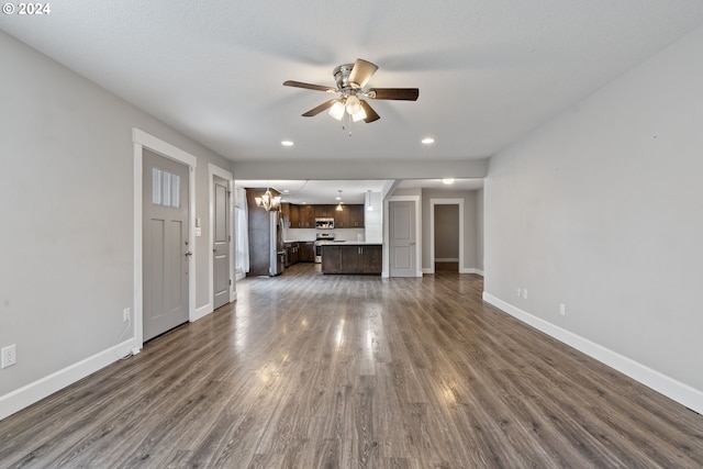 unfurnished living room featuring ceiling fan with notable chandelier and dark hardwood / wood-style flooring