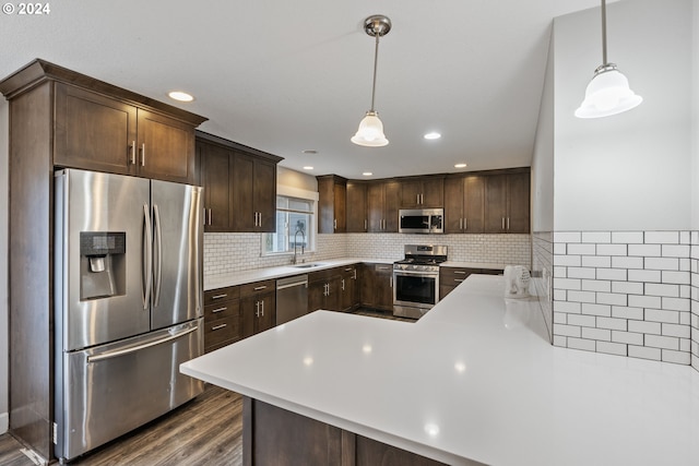 kitchen with sink, appliances with stainless steel finishes, hanging light fixtures, dark brown cabinetry, and kitchen peninsula