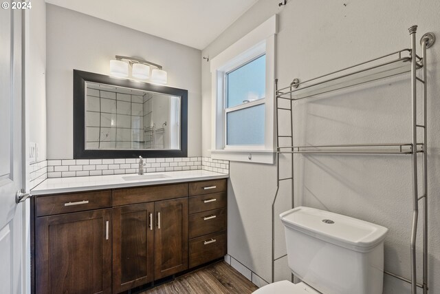 bathroom featuring hardwood / wood-style flooring, vanity, toilet, and decorative backsplash