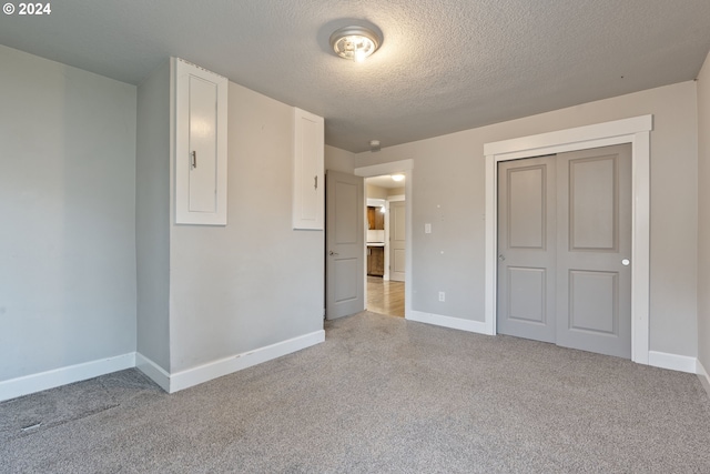 unfurnished bedroom with light colored carpet, a textured ceiling, and a closet