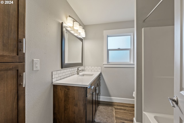 full bathroom featuring vaulted ceiling, shower / bathtub combination, backsplash, hardwood / wood-style flooring, and vanity