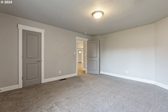 carpeted empty room with a textured ceiling