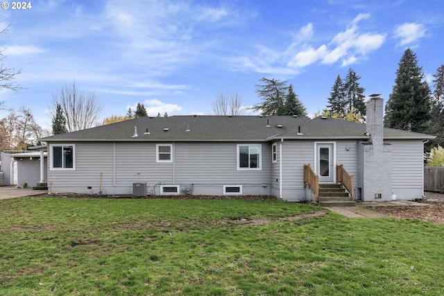 back of property with central AC and a yard