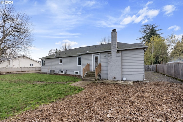 rear view of house with central AC and a yard