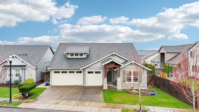 craftsman inspired home featuring fence, a garage, concrete driveway, a front lawn, and a shingled roof