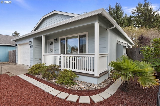 view of front of home with covered porch, fence, an attached garage, and concrete driveway