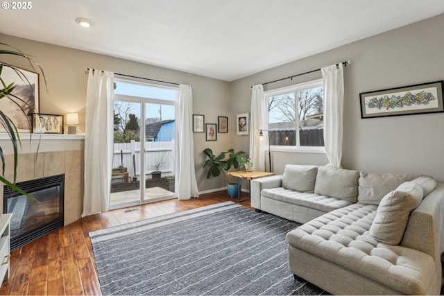 living area featuring a tiled fireplace, plenty of natural light, baseboards, and hardwood / wood-style floors