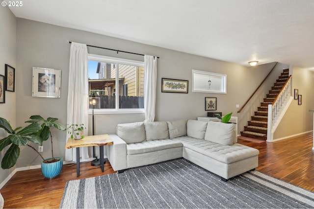 living area featuring baseboards, wood finished floors, and stairs