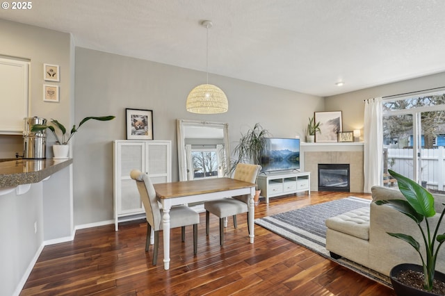 dining space with baseboards, plenty of natural light, wood finished floors, and a fireplace