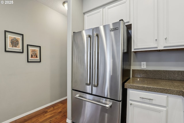 kitchen with baseboards, freestanding refrigerator, dark wood-type flooring, white cabinetry, and dark countertops