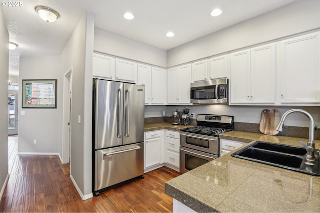 kitchen featuring dark wood-type flooring, tile countertops, appliances with stainless steel finishes, and a sink