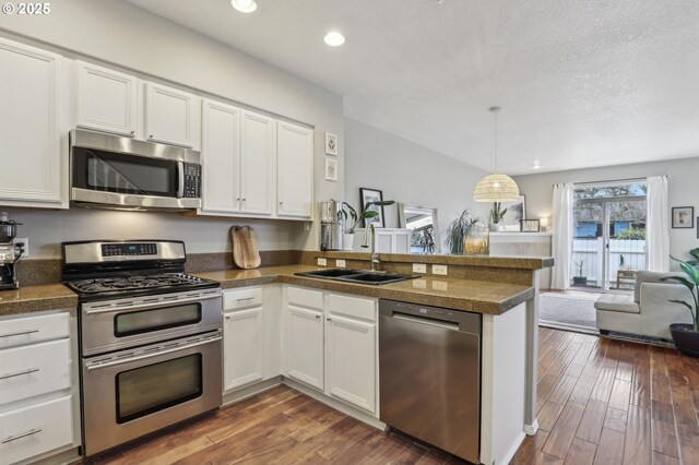 kitchen featuring tile counters, a peninsula, appliances with stainless steel finishes, and a sink