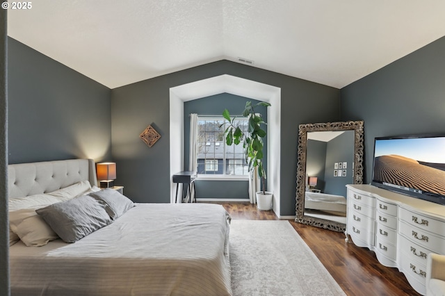 bedroom featuring visible vents, dark wood-type flooring, and vaulted ceiling