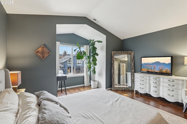 bedroom featuring vaulted ceiling, wood finished floors, visible vents, and baseboards