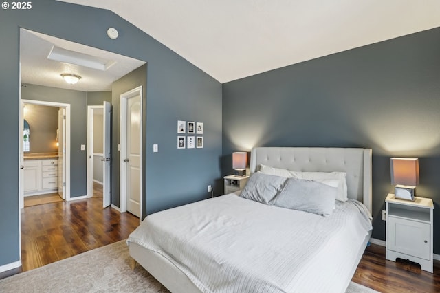 bedroom with baseboards, attic access, lofted ceiling, and wood finished floors