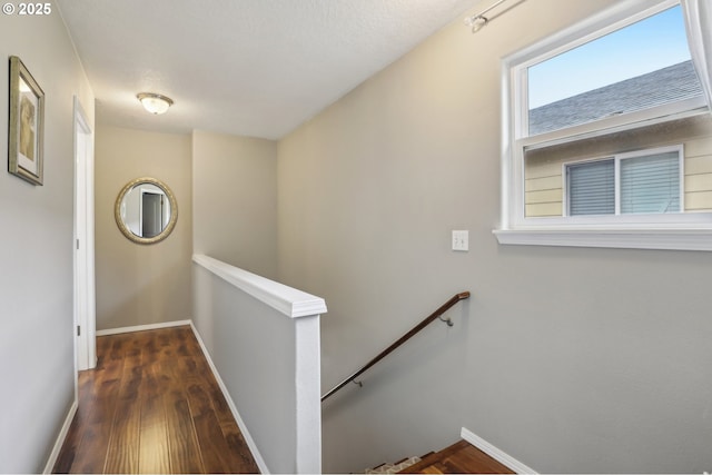 corridor featuring wood finished floors, an upstairs landing, and baseboards