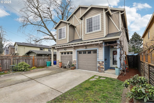 view of front of home featuring stone siding, driveway, a garage, and fence