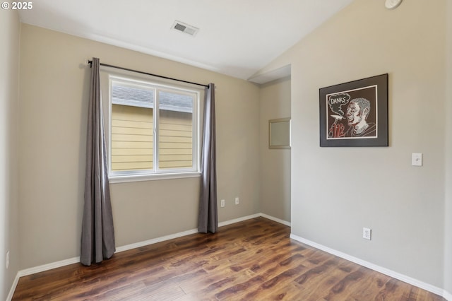 empty room with visible vents, baseboards, dark wood-style flooring, and vaulted ceiling