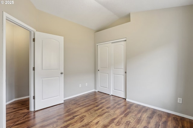 unfurnished bedroom featuring vaulted ceiling, wood finished floors, a closet, and baseboards