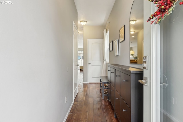 hallway featuring dark wood finished floors and baseboards