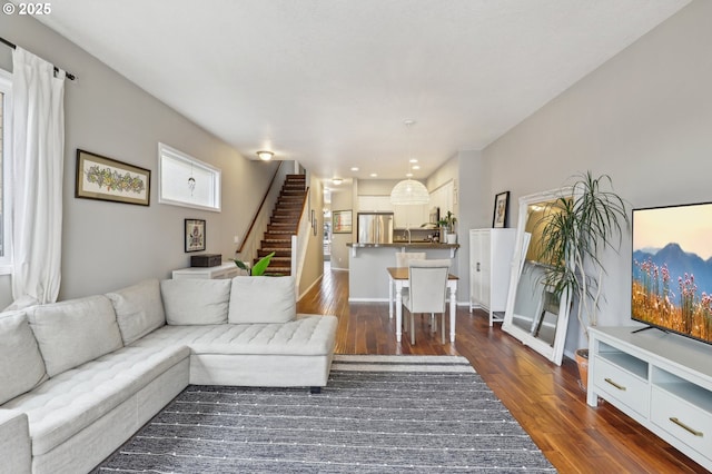 living area featuring dark wood finished floors, stairway, and baseboards