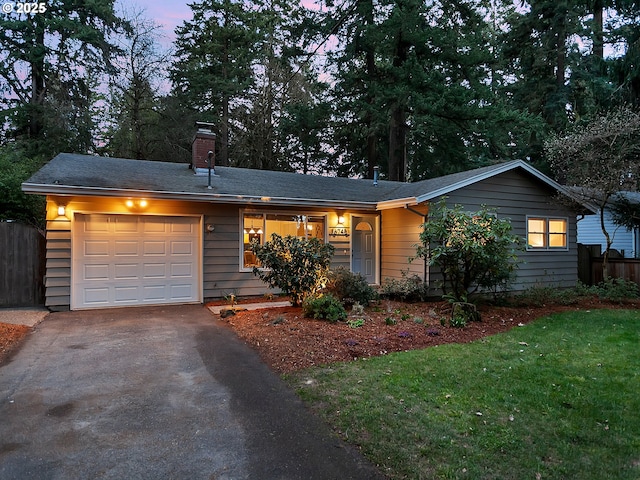 ranch-style house with fence, a front yard, a chimney, driveway, and an attached garage