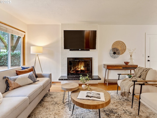 living area with a brick fireplace and wood finished floors