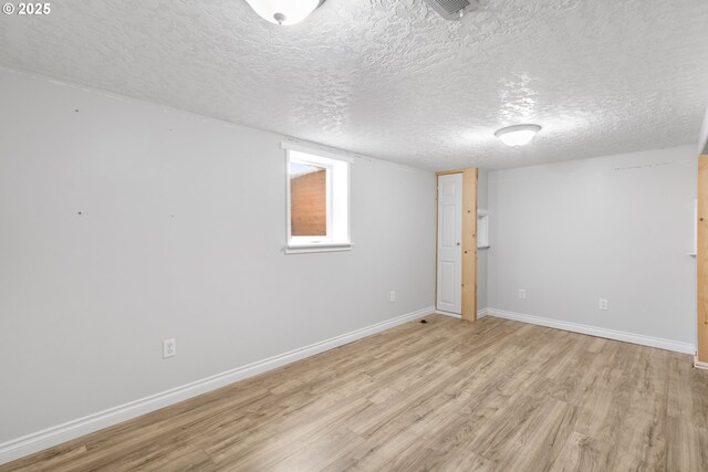 basement featuring light wood-type flooring and a textured ceiling