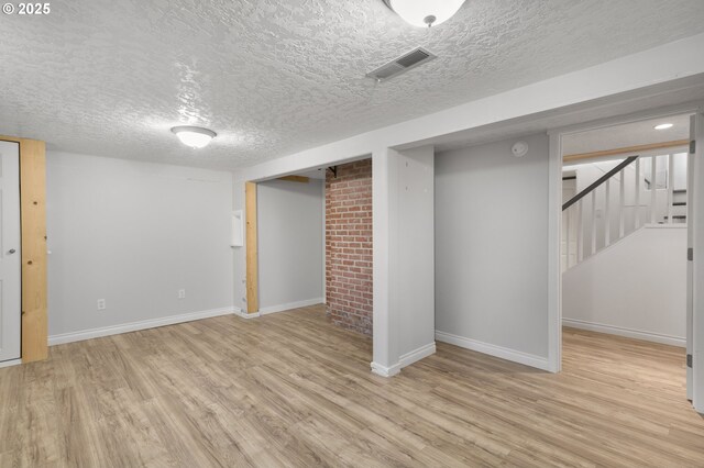 unfurnished living room with wooden walls, a fireplace, light hardwood / wood-style floors, and a textured ceiling